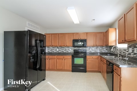 A kitchen with a black refrigerator and wooden cabinets.