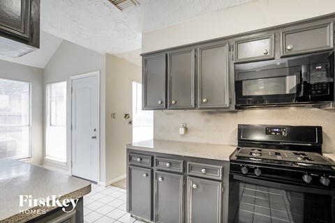 A kitchen with a black stove top oven and microwave above it.