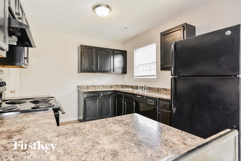 A kitchen with black appliances and a marble countertop.