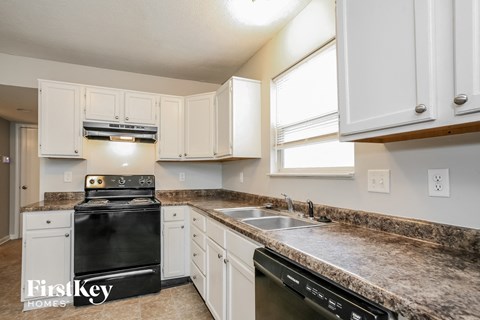 a kitchen with white cabinets and granite counter tops and black appliances