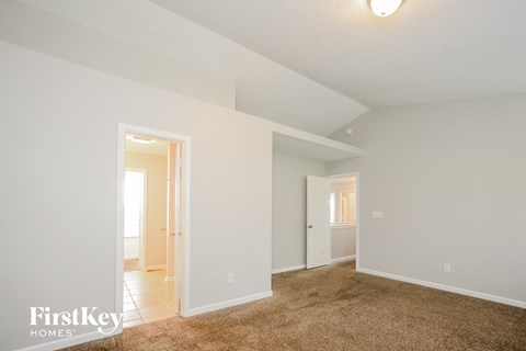 a master bedroom with a carpeted floor and a door to a bathroom