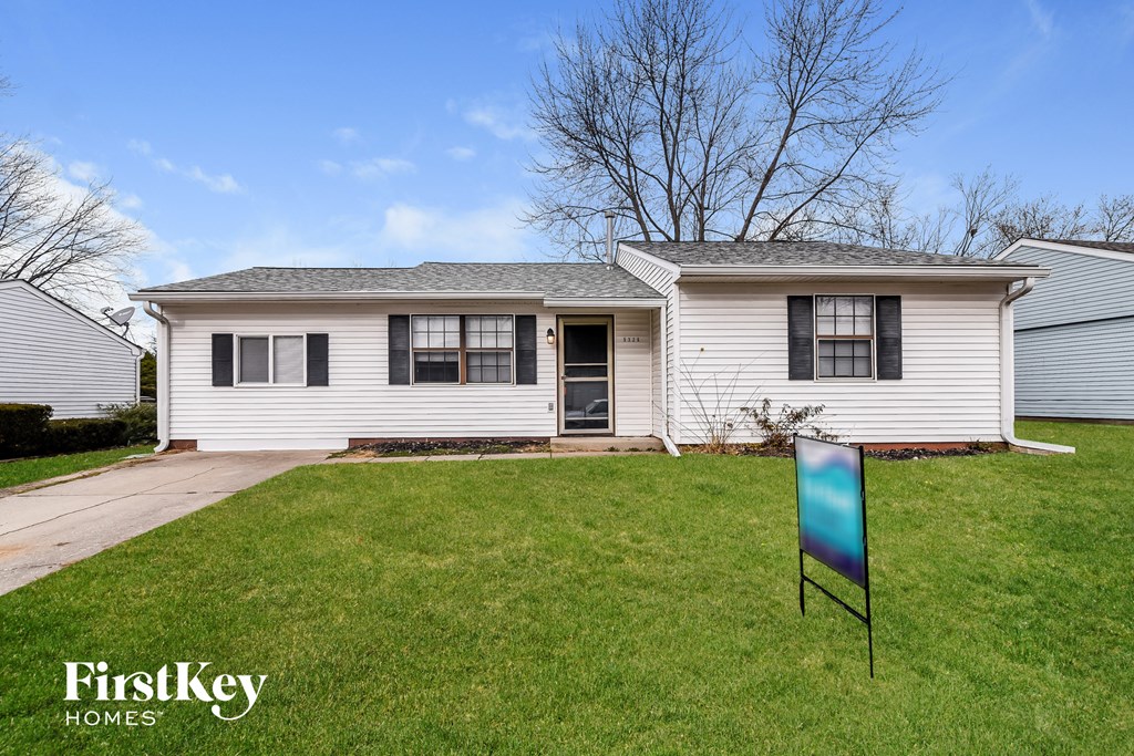 A white house with a grey roof and a sign that says FirstKey Homes.