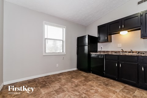 A kitchen with black cabinets and a tiled floor.