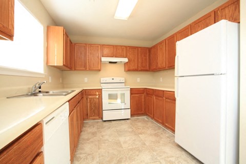 A kitchen with wooden cabinets and white appliances.