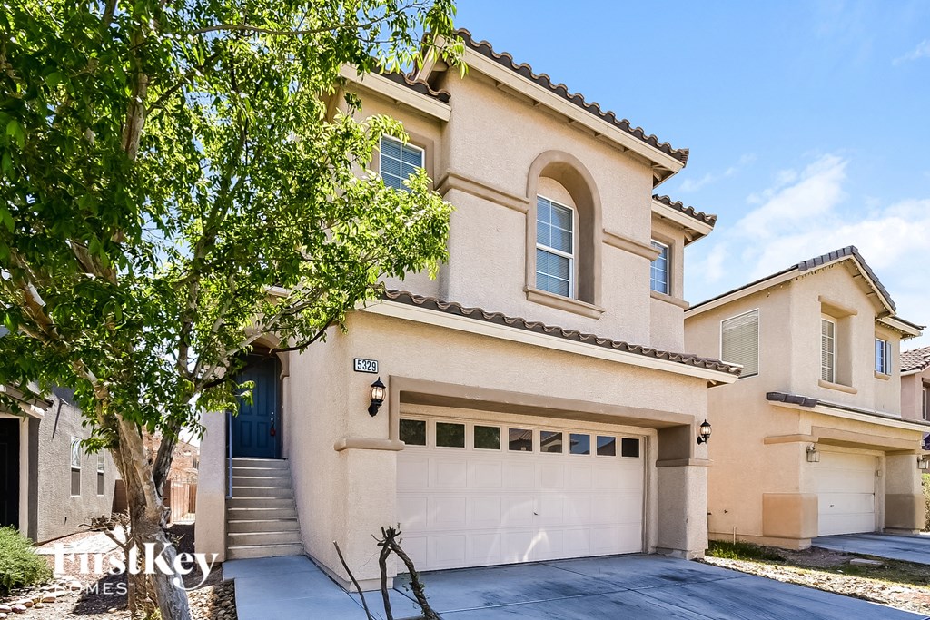 a beige house with a garage door and a tree