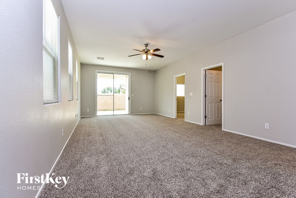 a spacious living room with carpet and a ceiling fan