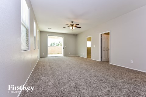 a spacious living room with carpet and a ceiling fan