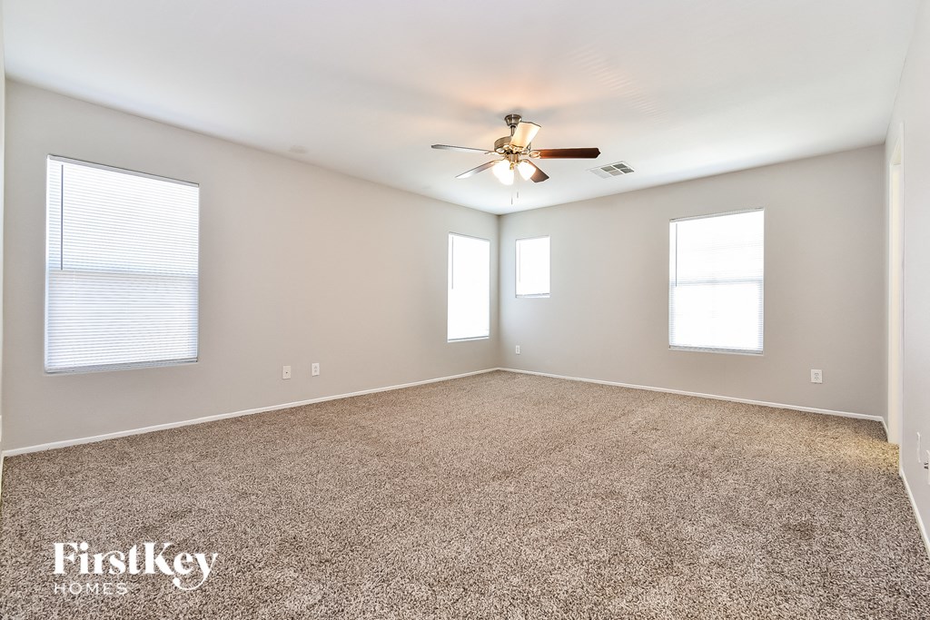 the spacious living room with ceiling fan and carpet