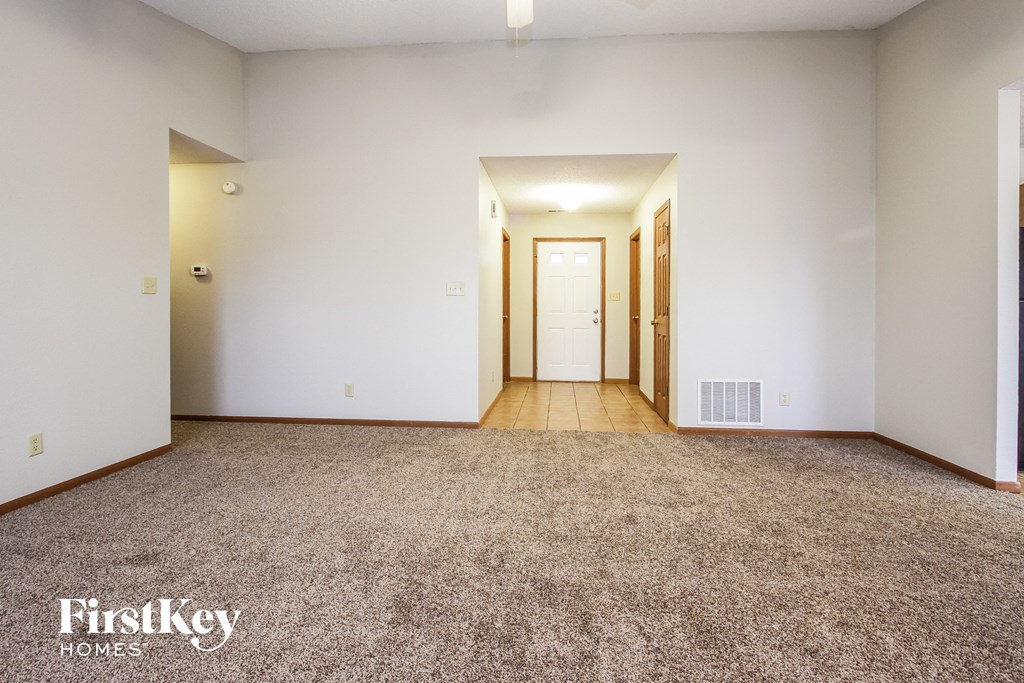 an empty living room with carpet and white walls