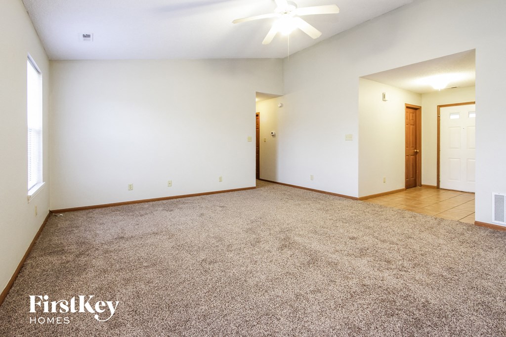 an empty living room with carpet and white walls