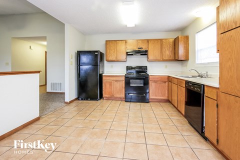 a kitchen with wooden cabinets and a black refrigerator