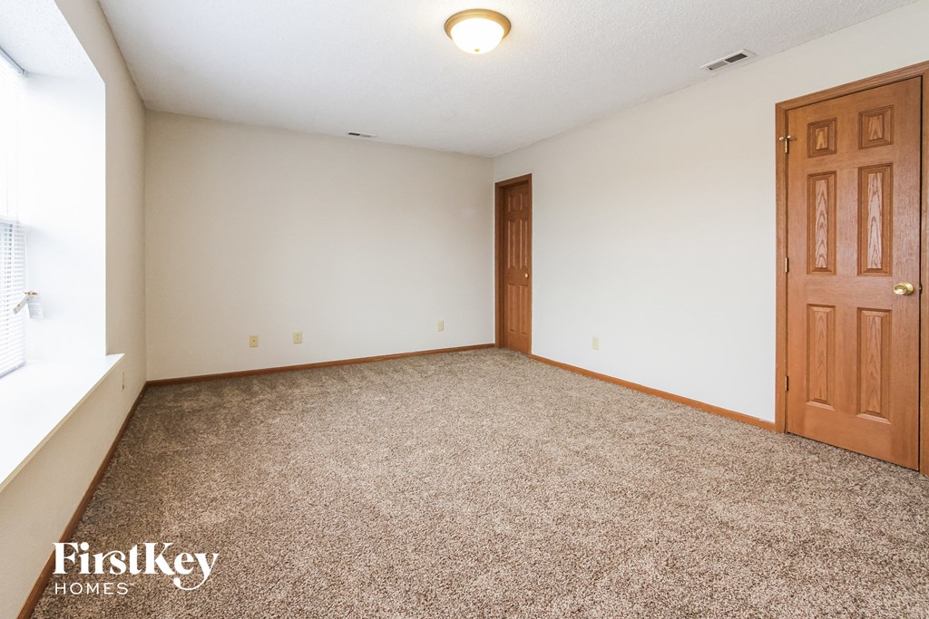 a bedroom with a carpeted floor and a wooden door