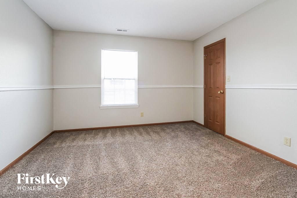 a bedroom with white walls and a window and a door
