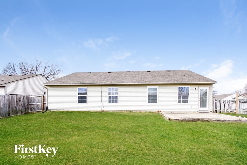 the backyard of a white house with a yard and a patio