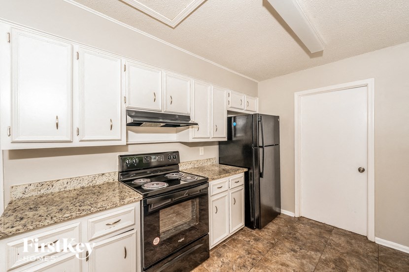 a kitchen with white cabinets and a black refrigerator