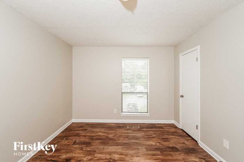 a bedroom with a wood floor and a window