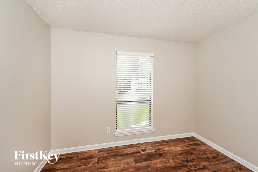 a bedroom with a window and a wooden floor