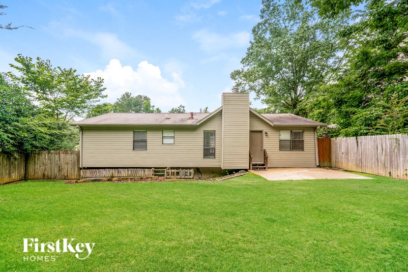 a small house in a fenced in backyard with a grassy yard