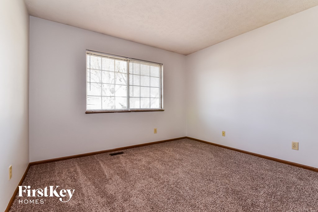 the living room is spacious and clean with carpet and a window