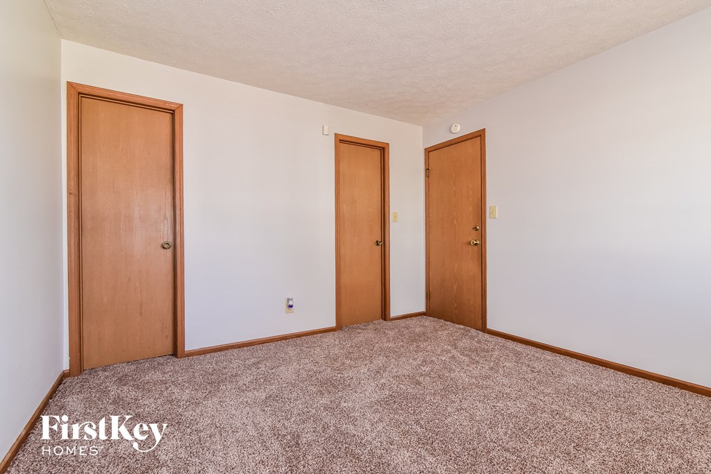a bedroom with two doors on the wall and a carpeted floor