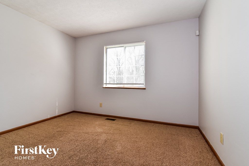 the living room of a home with white walls and a window