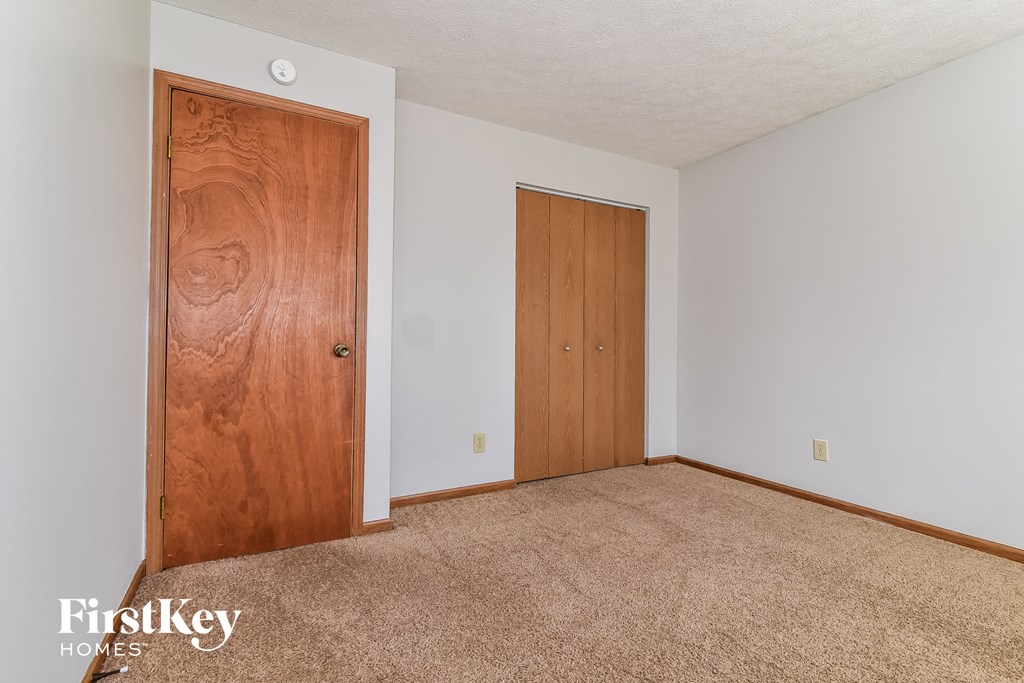 a bedroom with carpet and a door to a closet