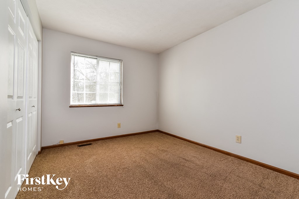 a bedroom with white walls and carpet and a window