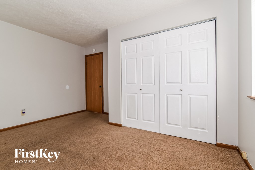 a bedroom with a door to a closet and a carpeted floor