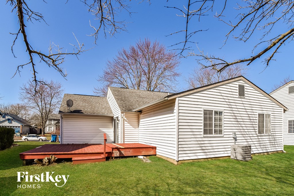 a backyard with a white house and a wooden deck