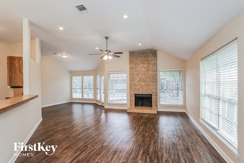 A spacious living room with wood flooring and a fireplace.