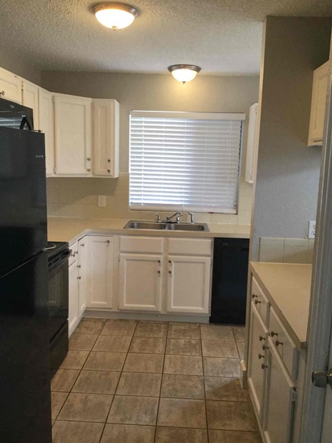 a kitchen with white cabinets and a sink and a window