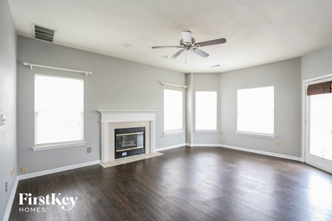 an empty living room with a ceiling fan and a fireplace