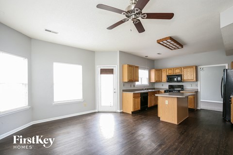 an empty kitchen with wood floors and a ceiling fan