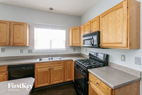a kitchen with wooden cabinets and black appliances and a window