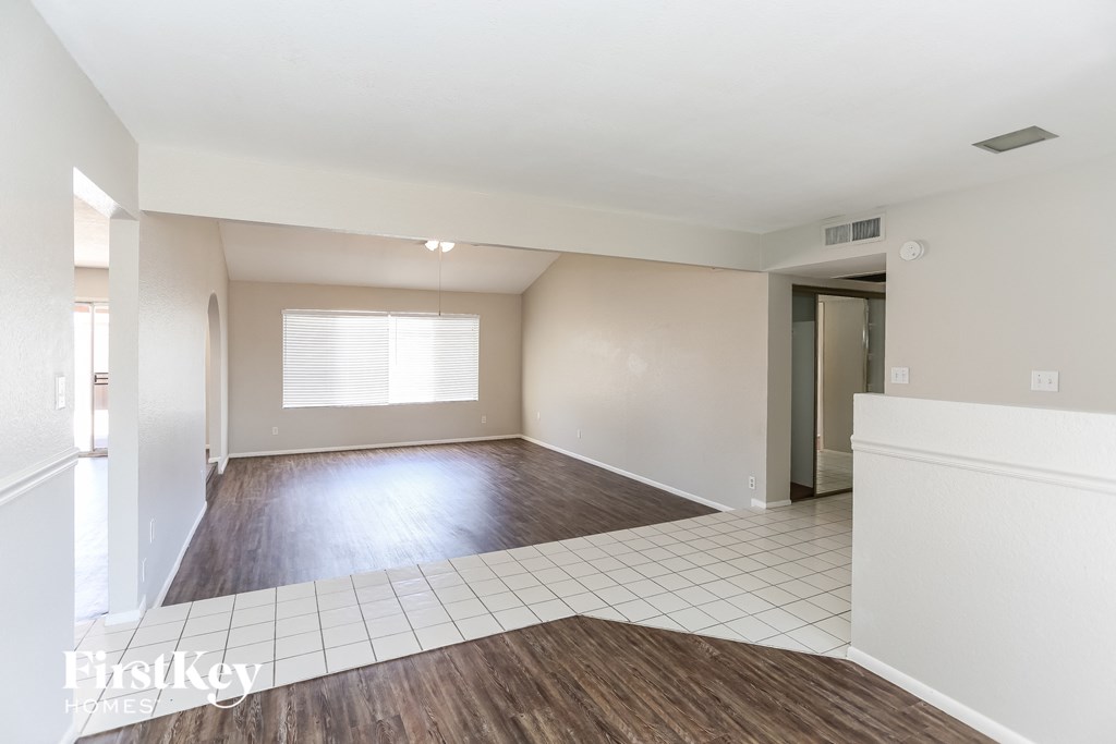 A spacious room with wooden flooring and white walls.