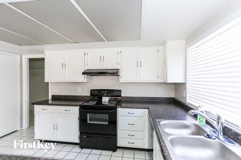A kitchen with white cabinets and black appliances.