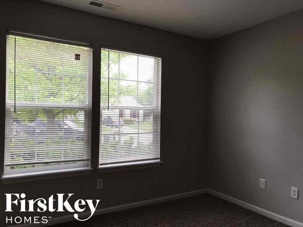 an empty room with two windows with blinds