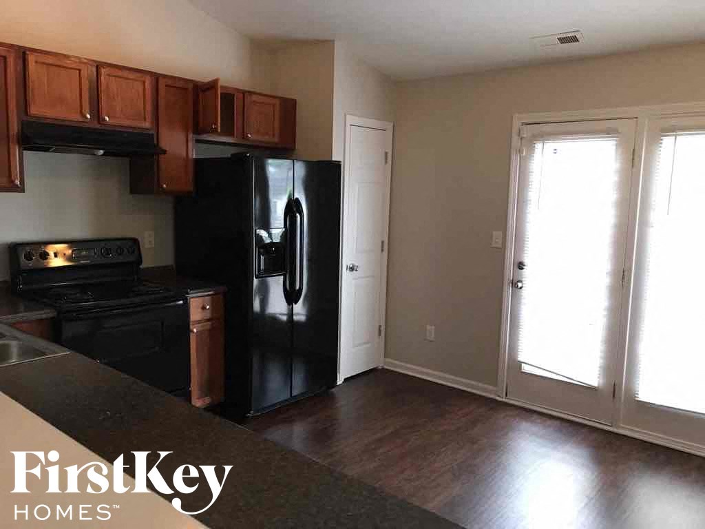an empty kitchen with black appliances and wood floors