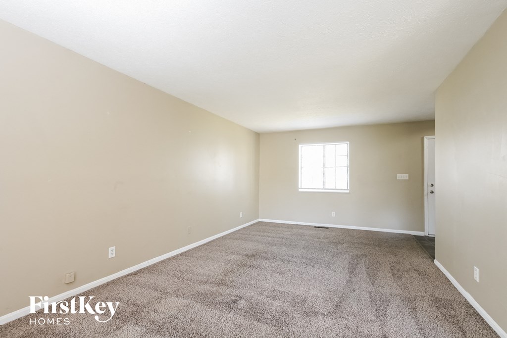 an empty living room with carpet and a window