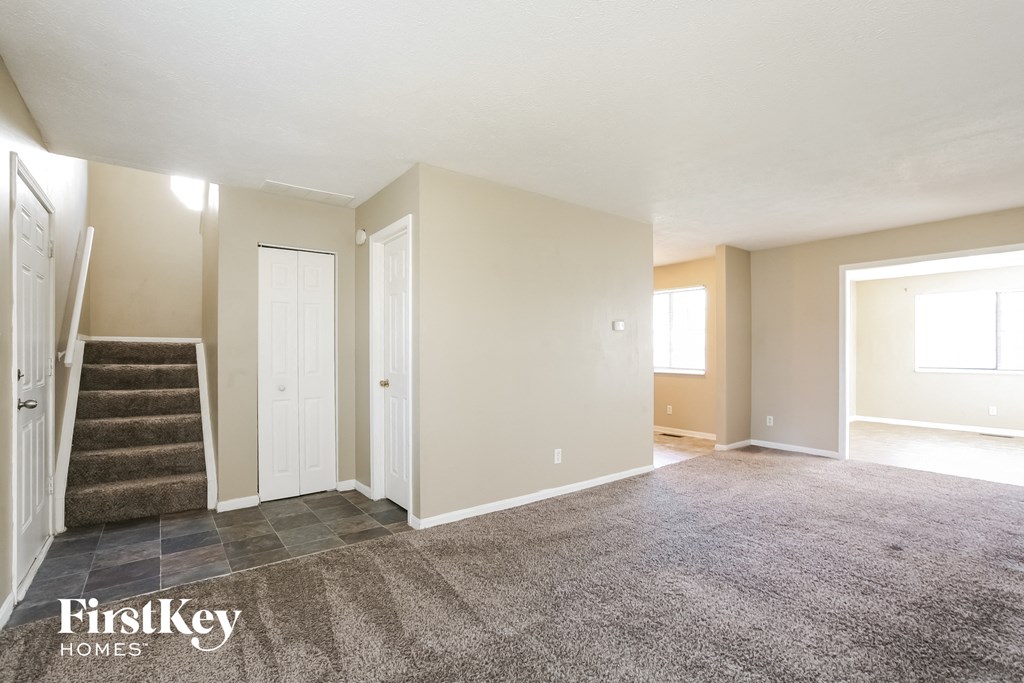 an empty living room with a staircase and a carpeted floor