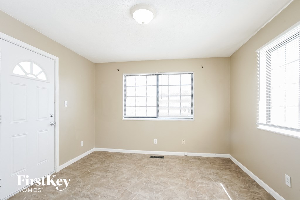 a empty living room with a white door and a window