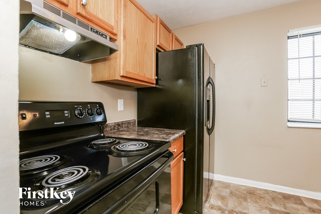 a kitchen with black appliances and wood cabinets and a black refrigerator