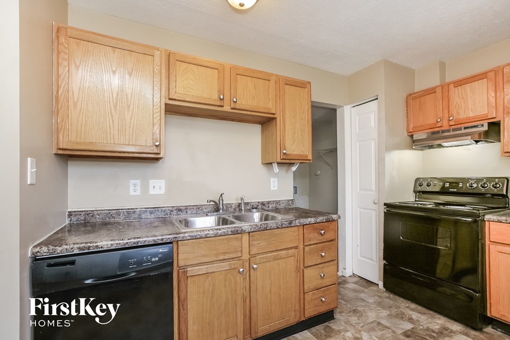 an empty kitchen with wooden cabinets and black appliances