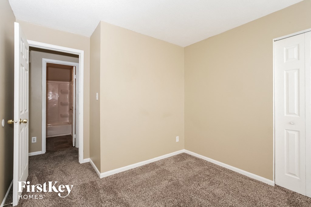 a bedroom with carpet and a door to the bathroom
