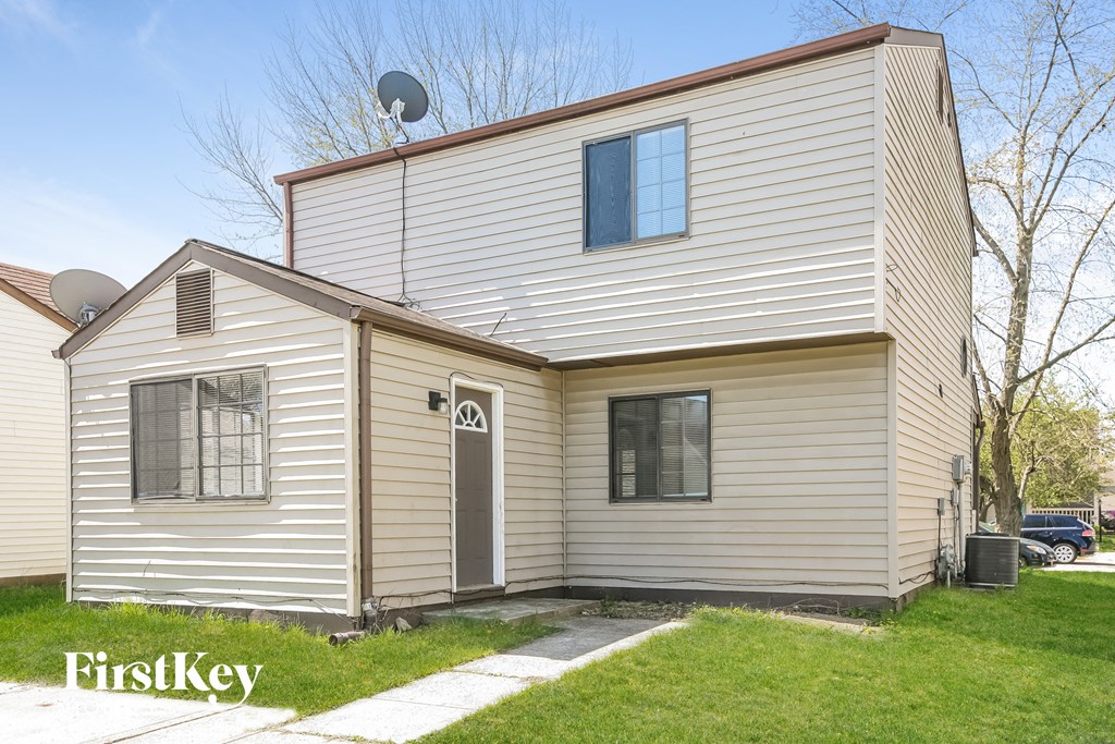 front view of a white house with white siding and a door and a lawn