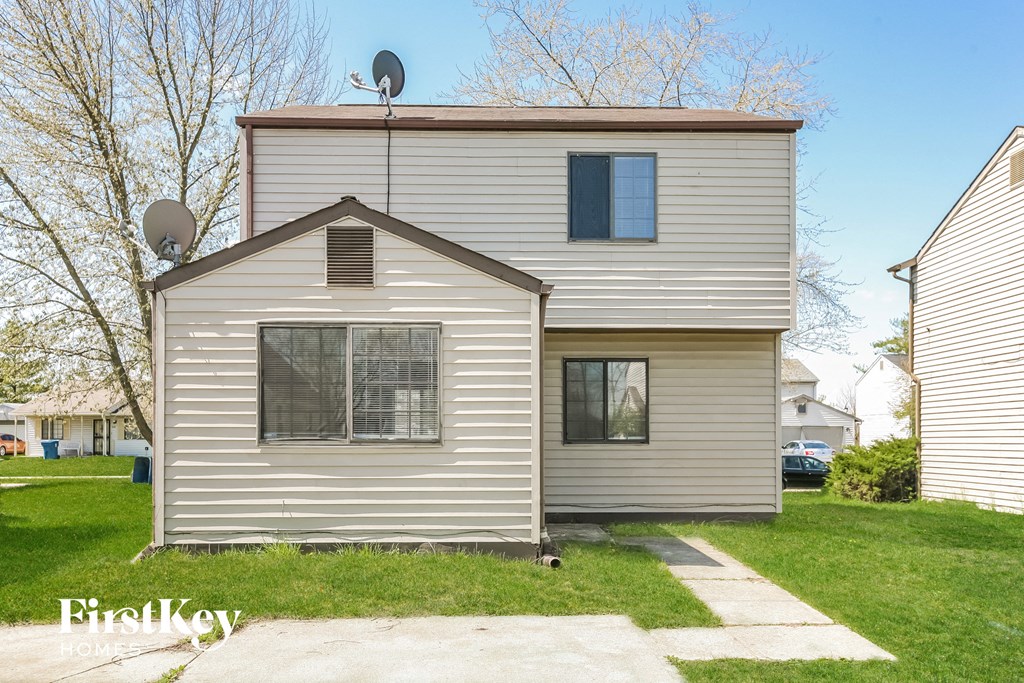 front view of a white house with gray siding and a yard with grass