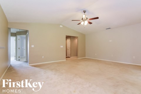 A spacious room with a ceiling fan and two doors.