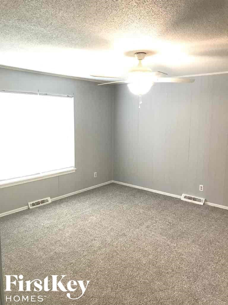 A room with a carpet floor and a ceiling fan.