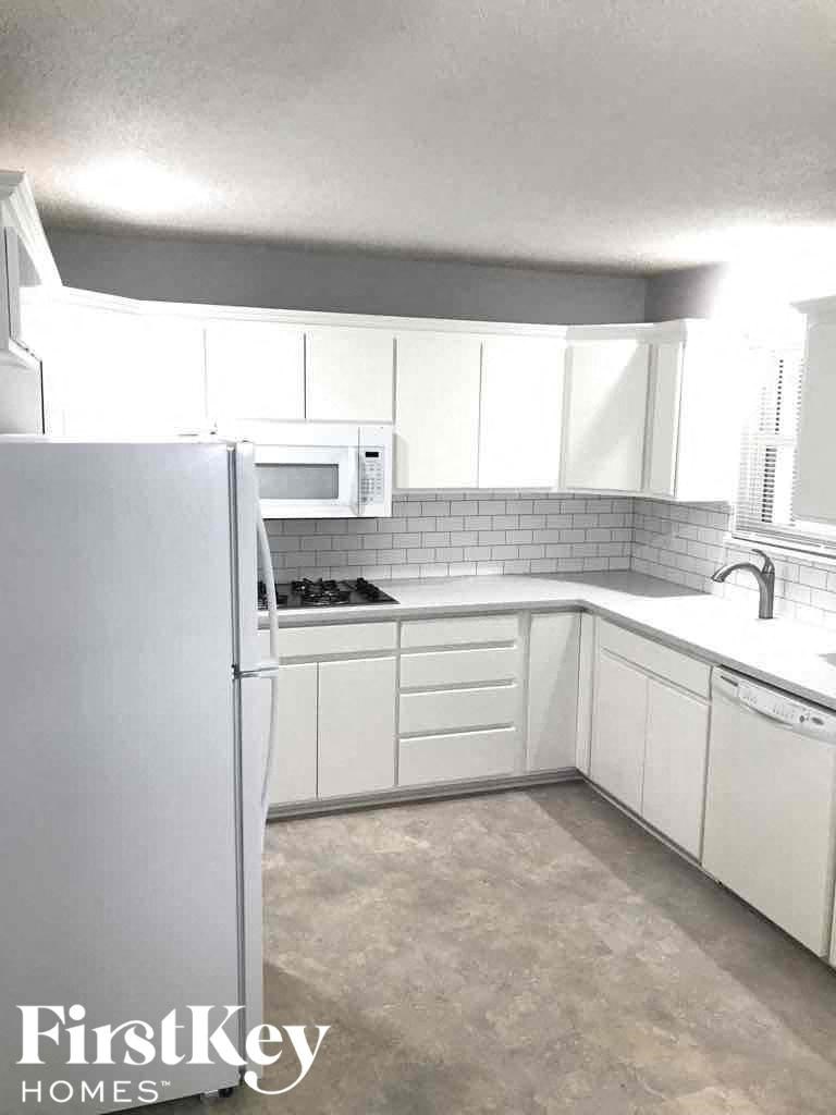 A kitchen with white appliances and cabinets.
