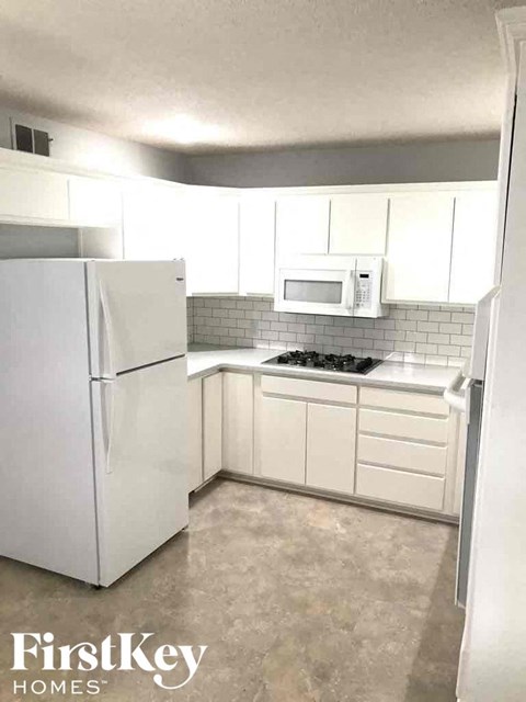 A kitchen with a white fridge, microwave, and stove top oven.